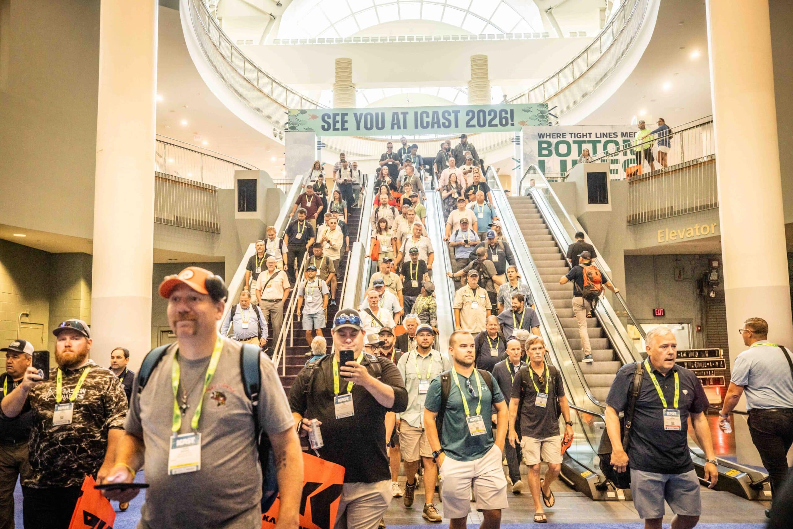 people walk down escalator at icast 2025